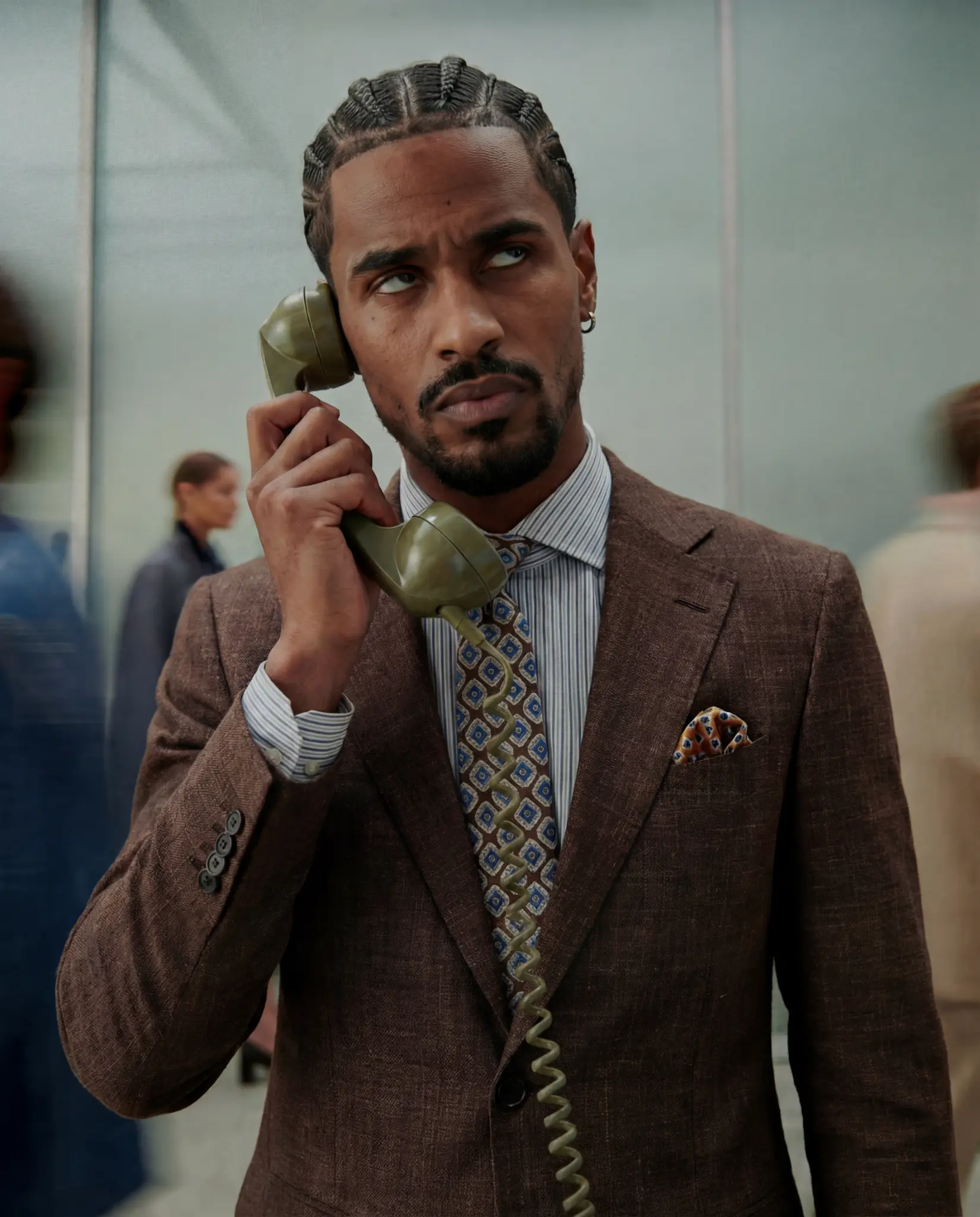 Professional in a brown suit holding an office phone and looking annoyed.
